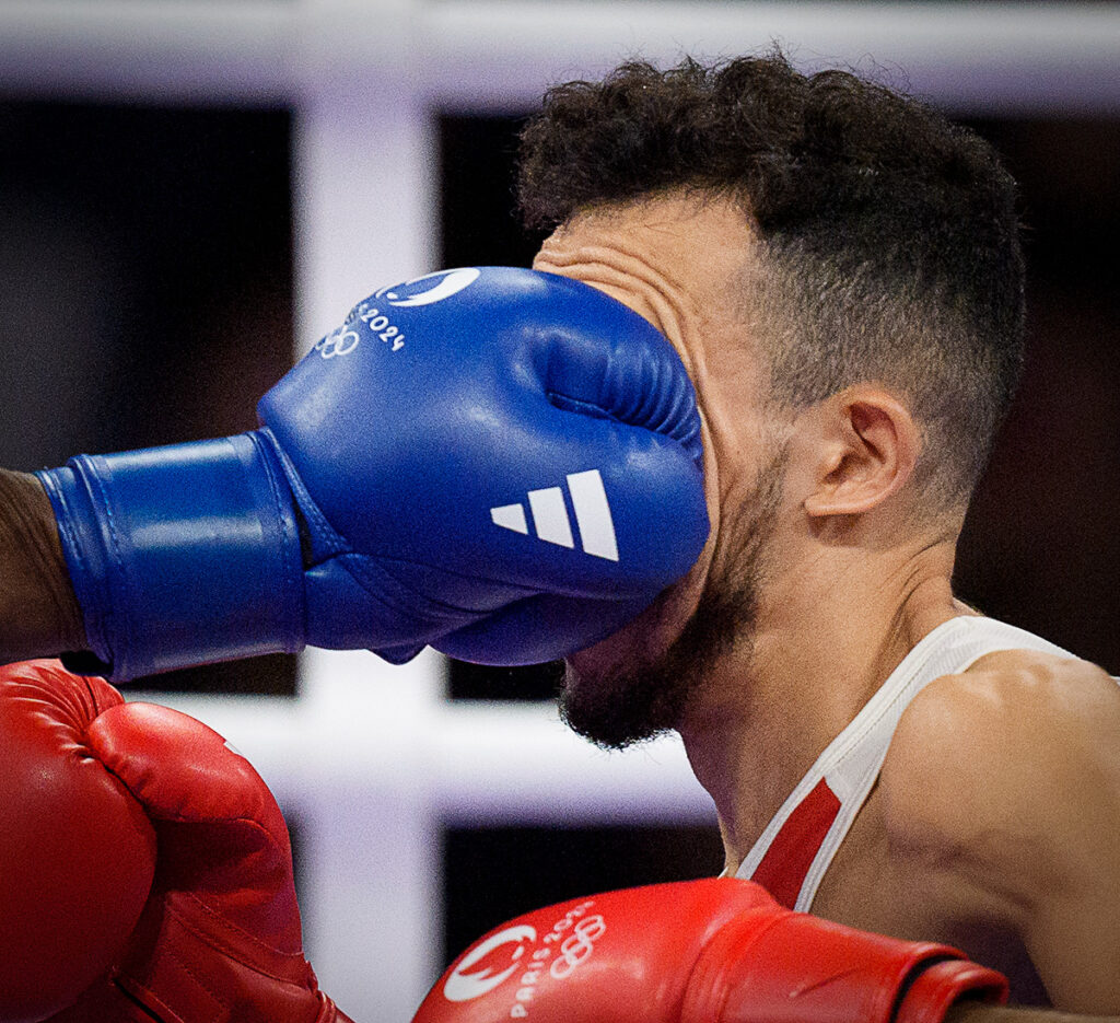 France's Billal Bennama takes a punch from USA's Roscoe Hill during the Men's 51kg - Preliminaries at the Paris 2024 Summer Olympics. Bennama went on to win the match. Photo by Nick Didlick